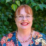 Picture of Ness with tree leaves in the background, Ness has a brilliant smile and makes you want to have a cuppa with her